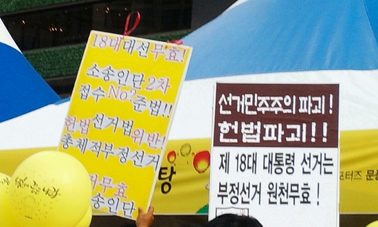 시민이 “제18대 대통령선거는 원천무효라는 ”피켓을 들고 시위를 벌이고 있다