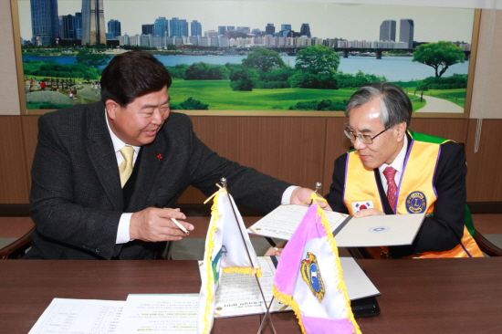 조길형 구청장과 이규섭 협회 총재가 협약서에 서명하고 교환하고 있다.