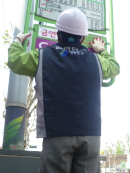 공공근로 참여자가 버스정류장에 금연안내판을 부착하고 있다.  &copy;영등포구