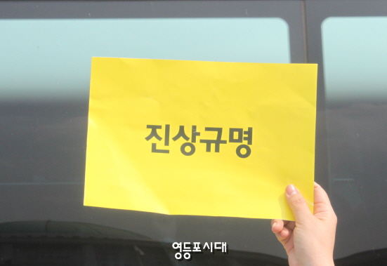 16일 국회 앞에서 아이들을 맞이한 한 학부모가 버스에 오른 학생들을 향해 “진상규명”이라는 노란 손팻말을 들어 보이고 있다.