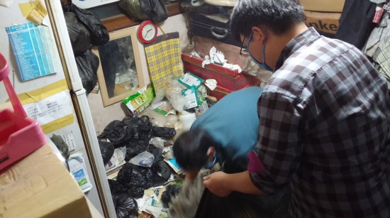 영등포본동 주민센터 관계자와 자원봉사자가 2년 동안 방치해온 쓰레기 더미를 치우고 있다.