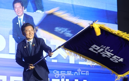 ▲정청래 신임 당대표가 김병기 원내대표로부터 전달받은 당기를 흔들고 있다./사진=공동취재단